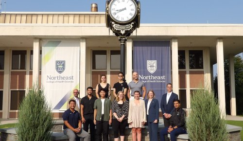 a Northeast cohort and campus leaders pose at the clock plaza