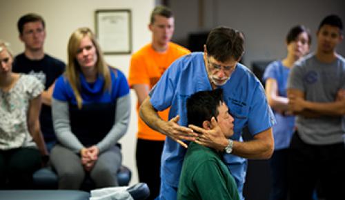 A professor demonstrating a chiropractic adjustment to students