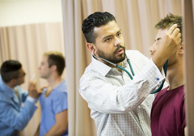 A student practicing chiropractic care on another student with others in the background