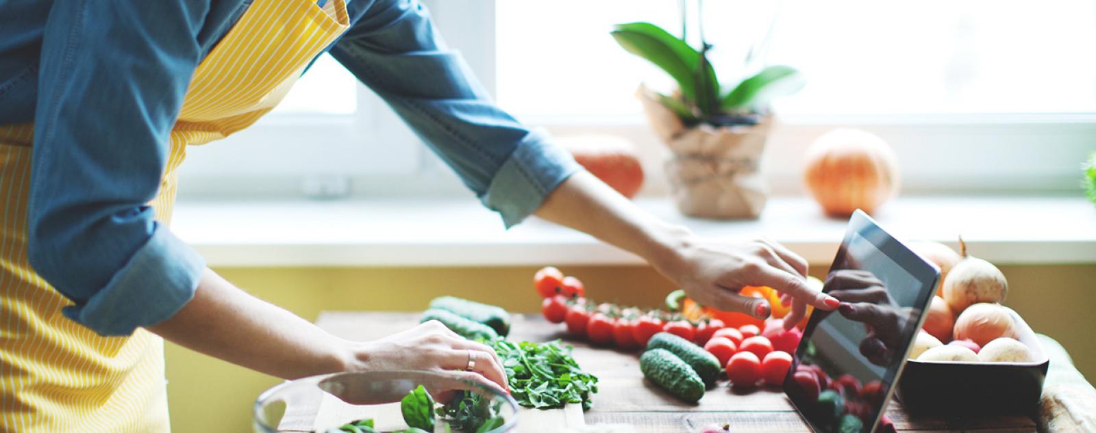A woman pressing a tablet surrounded by fruit
