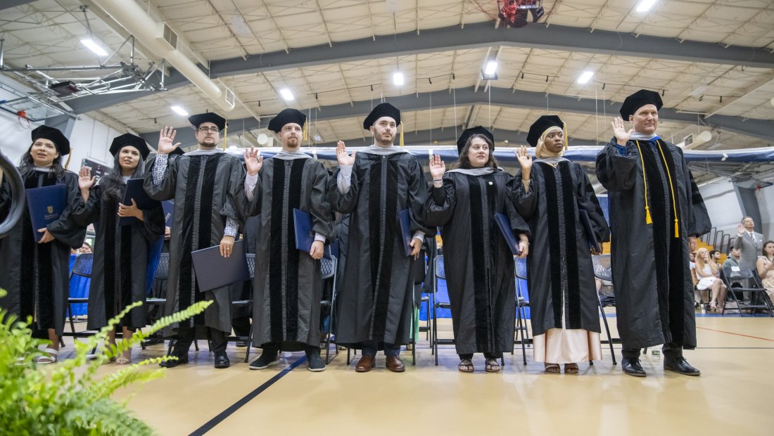 graduates with right hands raised reciting the oath