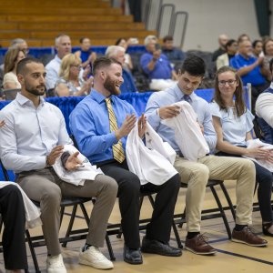 students clapping and smiling, holding their white coats