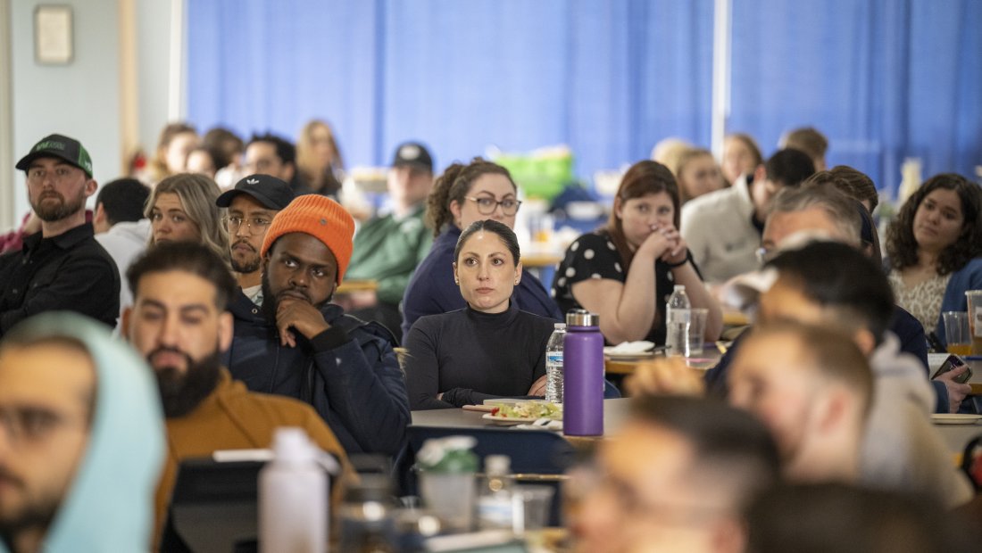students seated at tables, listening intently