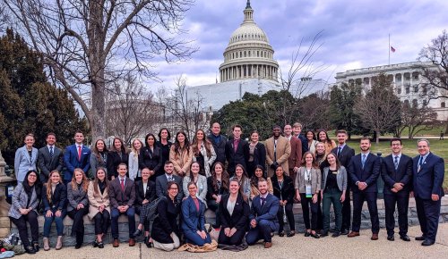 a group of students and faculty standing in front of the Capitol Building