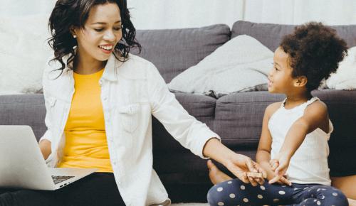 A woman working on a laptop while entertaining children