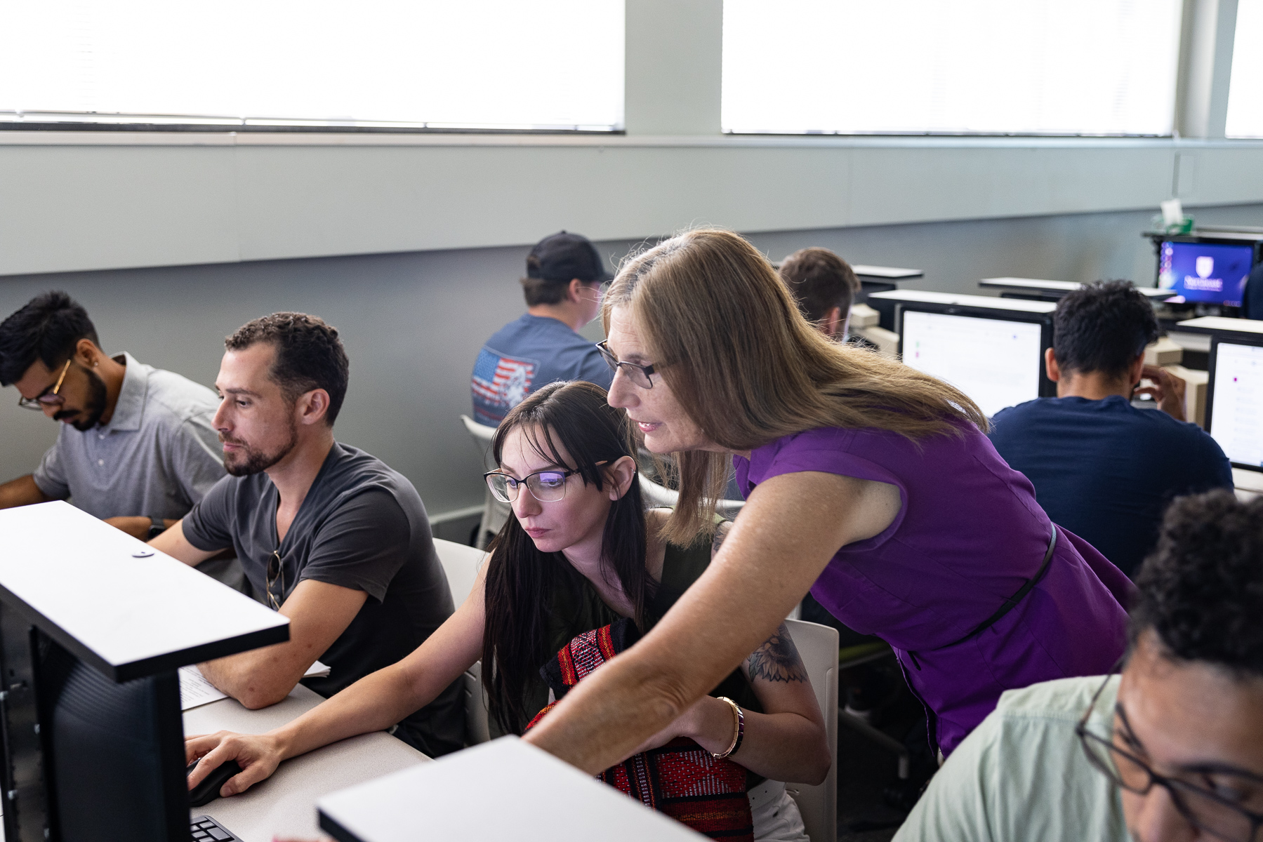 instructor helping a student in a computer lab during class