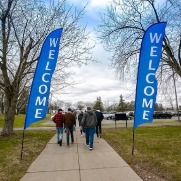 students walking on campus next to Welcome banners