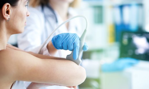 A sonographer using an ultrasound probe on a patient's elbow