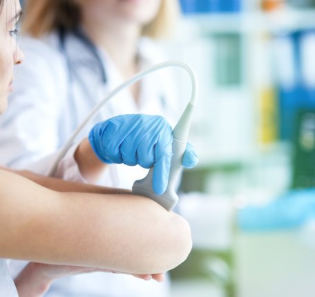 a sonographer using an ultrasound probe on a patient's elbow