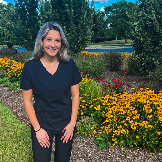 Bridget Ivanyi standing in front of flowers on campus.